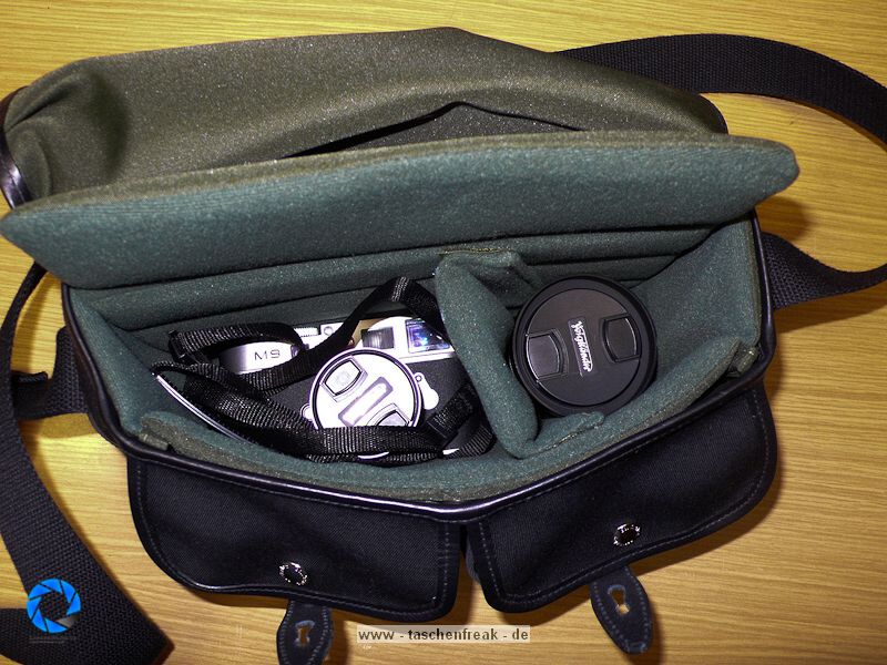 BILLINGHAM HADLEY SMALL\n\nFoto und Text von Jrg Langer - www.taschenfreak.de\n\nKommentar:\n\nDie kleinste Billingham aus der bekannten Hadley Serie. Typisch fr Billingham, der edle aber sehr robuste Stoff, die unauffllige "Bauform", die Lederbeschlge fr den Verschluss und der grne "Innenraum" der sehr weich und schtzend fr die edlen Teile darin ist.\n\nDie "Small Hadley" ist ideal fr eine kleine DSLR wie D40 oder D90 mit einem Kit oder Zoom bis max 18-200 VR oder ideal fr eine Systemkamera mit angesetzten Objektiv und einem weiteren Objektiv. Hinter dem Fotofach ist ein weiches flaches Fach zu finden welchen wirklich perfekt zugeschnitten fr das iPad ist und die beiden Fronttaschen nehmen gut Handy, Ersatzakku, Camera Connection Kit fr das iPad oder auch Geldbrse auf. \n\nDie Tasche ist sehe edel verarbeitet, dennoch praktisch und bequem zu nutzen. Der Gurt st fest und nicht abnehmbar und leider recht rutschig auf der Jacke. Dagegen hilft das optionale Schulterpolster fr den Gurt (das ich leider nicht mitbestellt habe....).\n\nAlso wer eine kleine Tasche fr seine kleinen Begleiter sucht wird mit der Hadley Small sicher sehr glcklich werden!